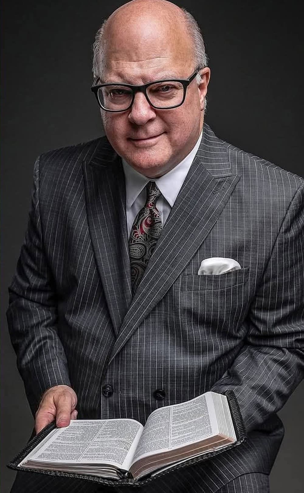 Dr. John N. Hamblin holding an open Bible